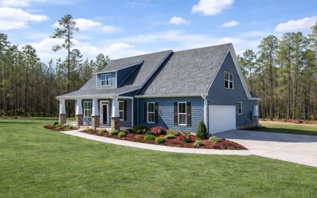 A beautiful blue two-story new construction home with white trim, attached garage, and well-maintained landscaping sits on a large grassy lawn surrounded by trees under a partly cloudy sky. This inviting property showcases the appeal of new homes with its spacious design and elegant features.