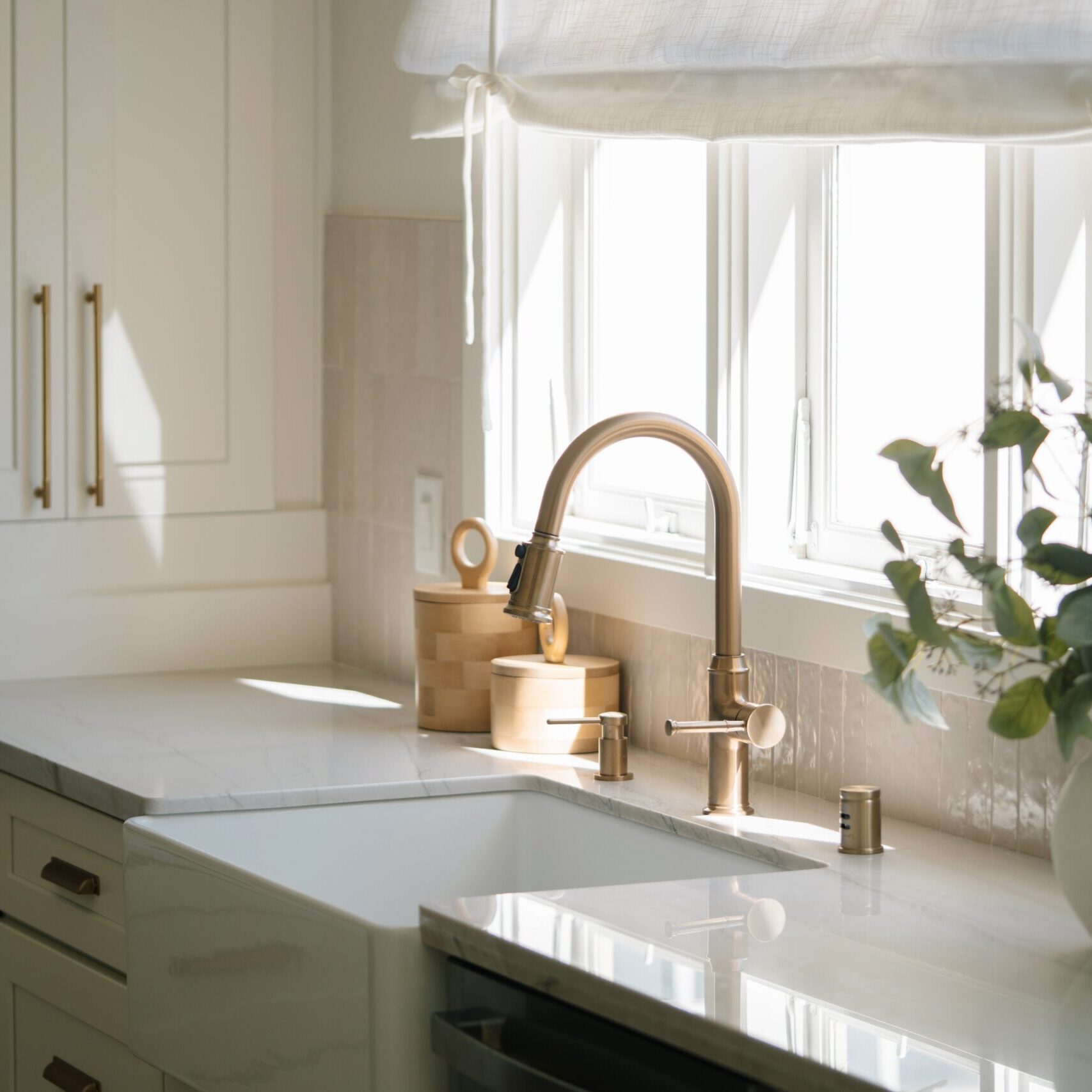 Bright,Modern,Kitchen,Interior,With,Farmhouse,Apron,Sink,And,Brass White quartz countertops with gold metal accents in a brightly lit kitchen.