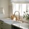 White quartz countertops with gold metal accents in a brightly lit kitchen.