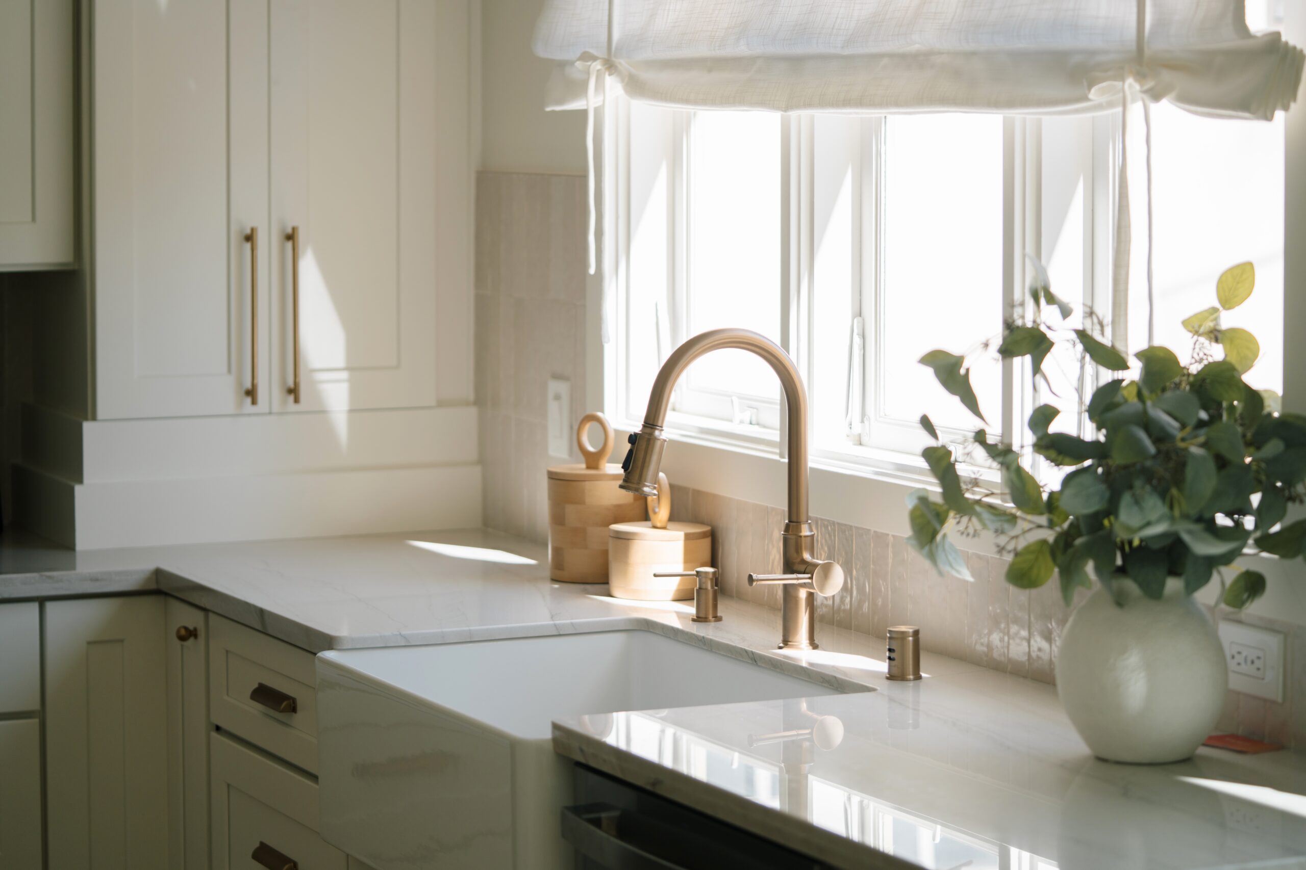 White quartz countertops with gold metal accents in a brightly lit kitchen.
